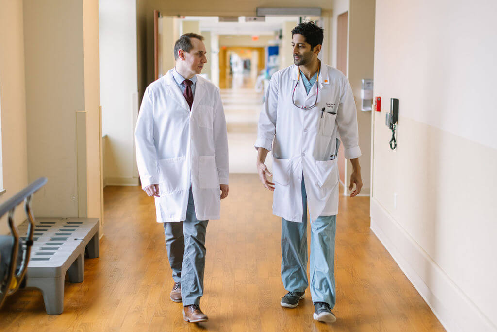Two doctors walking down a clinic hallway